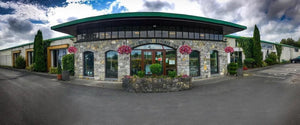Mullingar Pewter Visitor Centre façade. A beautiful stone work building with lovely hanging baskets and blue sky