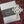 Load image into Gallery viewer, Mullingar Pewter Wall hanging cross with Celtic knot work and a Claddagh embellishment resting on a Mullingar Pewter presentation box and on a beautiful bed of pink heather