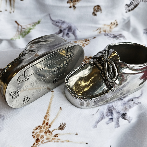 Pewter metal baby boot ornament with engraving to record the baby details. on a baby blanket with baby animals such as elephant, giraffe and zebra