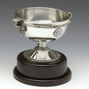 A REPLICA OF THE 8TH CENTURY CHALICE. THIS LARGE BOWL SHAPED CHALICE SITS ON A DECORATED STEM THAT IN TURN SITS ON A WOODEN BASE. THE TOTAL HEIGHT IS 10".  IDEAL AS A TROPHY OR AWARD FOR GOLF, FOOTBALL OR ANY SPORTING OCCASION  PEWTER METAL SILVER MADE IN IRELAND