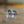 Load image into Gallery viewer, A pair of silver-toned tie pins with a Celtic claddagh design, resting on a reflective wooden surface with a blurred background.
