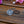 Load image into Gallery viewer, A silver Celtic knot circular hair tie clip with a black elastic band, resting on a rustic wooden surface with pink and purple flowers in the background.
