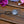 Load image into Gallery viewer, A silver-toned circular hair tie charm with an engraved heart design, attached to a black elastic band, displayed on a rustic wooden surface with decorative flowers.
