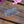 Load image into Gallery viewer, An ornate silver metal hair comb with engraved floral patterns on the bar, displayed on a rustic wooden surface with pink flowers in the corner.
