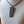 Load image into Gallery viewer, A rectangular black pendant necklace with an engraved circular symbol, displayed on a white fabric mannequin bust.
