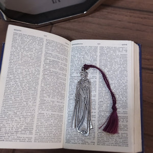 Queen Elizabeth II is captured in a Pewter metal Bookmark with a maroon coloured tassel. The bookmark is resting on a dictionary open on the word Queen 
