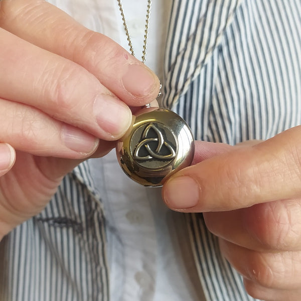 Lady holding a necklace of a pendant with a Irish knot work in silver colour Pewter Metal. 