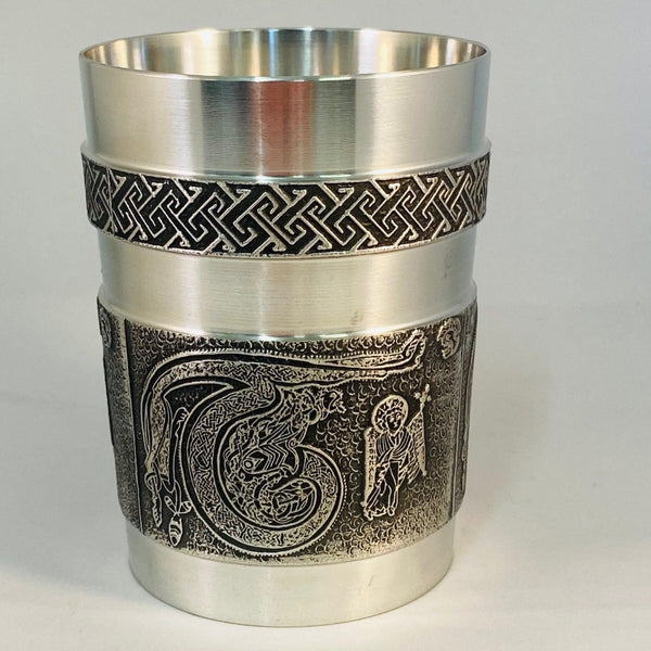 BOOK OF KELLS DRINKS BEAKER 10 FLUID OZ WITH THE LETTER T AROUND THE OUTSIDE OF THE BEAKER. THE BEAKER IS 4" TALL. POLISHED PEWTER SILVER RIMS WITH DECORATED FINISH.