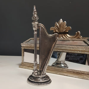 Pewter Harp Ornament made in Mullingar Pewter, Ireland. Sitting next to a mirrored jewellery box with a grey background