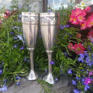 Handcrafted Pewter Champagne or wine flutes, silver in colour. Embossed with Celtic knot work inspired by the book of Kells. Taken with beautiful bright coloured flowers