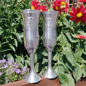 Mullingar Pewter Champagne Flute set with Claddagh Motif. Pictured with beautiful red flowers in the midday sun