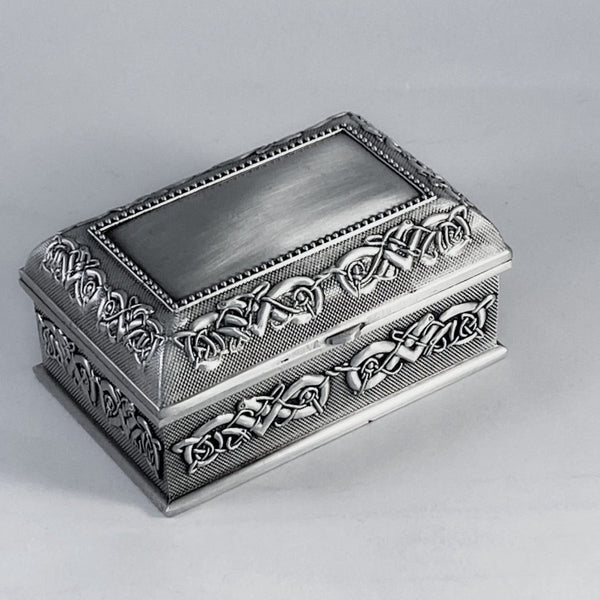3 1/2" LONG CELTIC JEWELRY BOX. THE BOX IS SURROUNDED WITH CELTIC BIRD LIKE CREATURES THAT ARE ENTWINED IN EACH OTHER. THE LID IS BEADED WITH A PLAIN CENTER FOR PERSONALIZING AND THE LID IS ALSO SURROUNDED IN CELTIC MOTIF. THE BOX IS PEWTER SILVERWARE POLISHED TO A SOFT CONTRAST LIKE FINISH